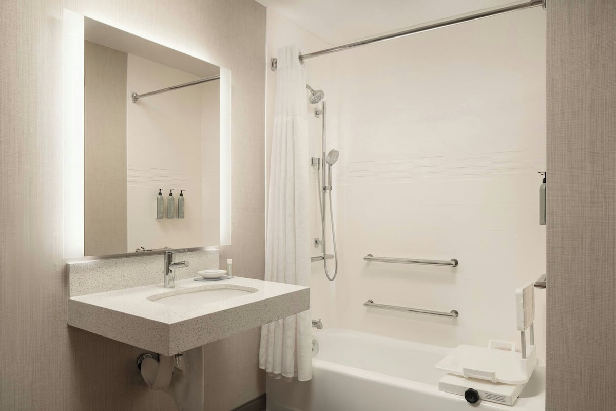 A modern bathroom with a sink, mirror, shower, and bathtub.
