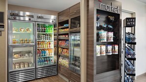 A section of a hotel with refrigerated display cases containing snacks and beverages, a 'Market' sign, and a 'Life WTR' water dispenser. - Residence Inn by Marriott Pasadena Arcadia (Arcadia)