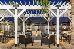 An outdoor patio area with a pergola, seating, and a pool.