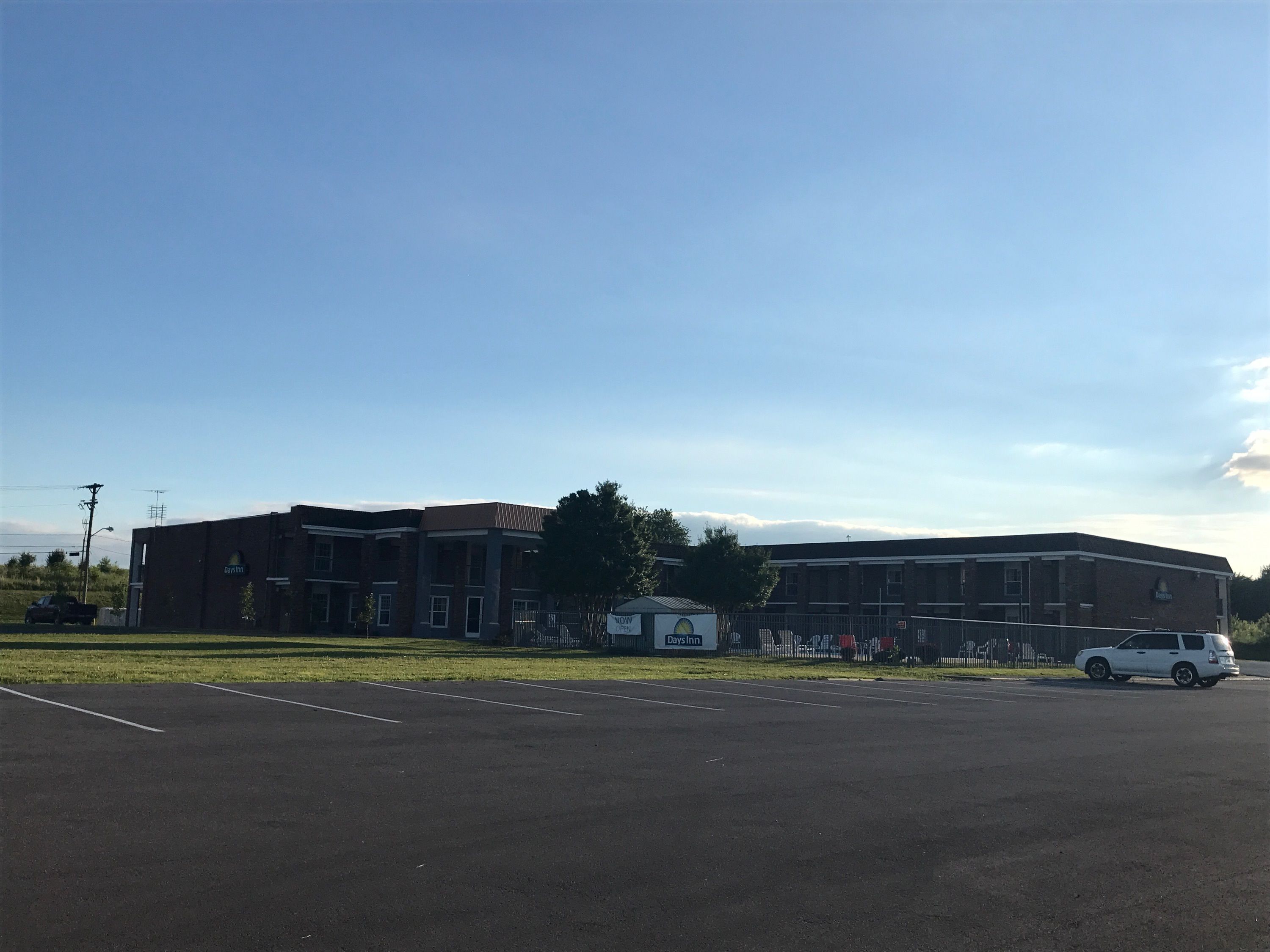 Edifício Days Inn com fachada de tijolos, estacionamento e céu claro.