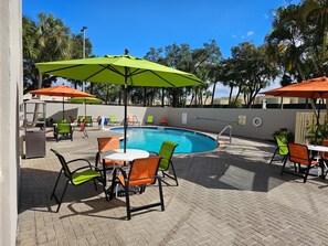 Ein Poolbereich mit Pool, Liegestühlen und Sonnenschirmen.