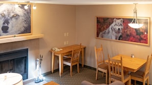 A cozy living room with a fireplace, wooden furniture, and a painting of a wolf.