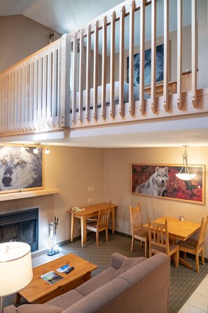 A cozy living room with a fireplace, wooden furniture, and a painting of a wolf. - Banff Rocky Mountain Resort (Banff)