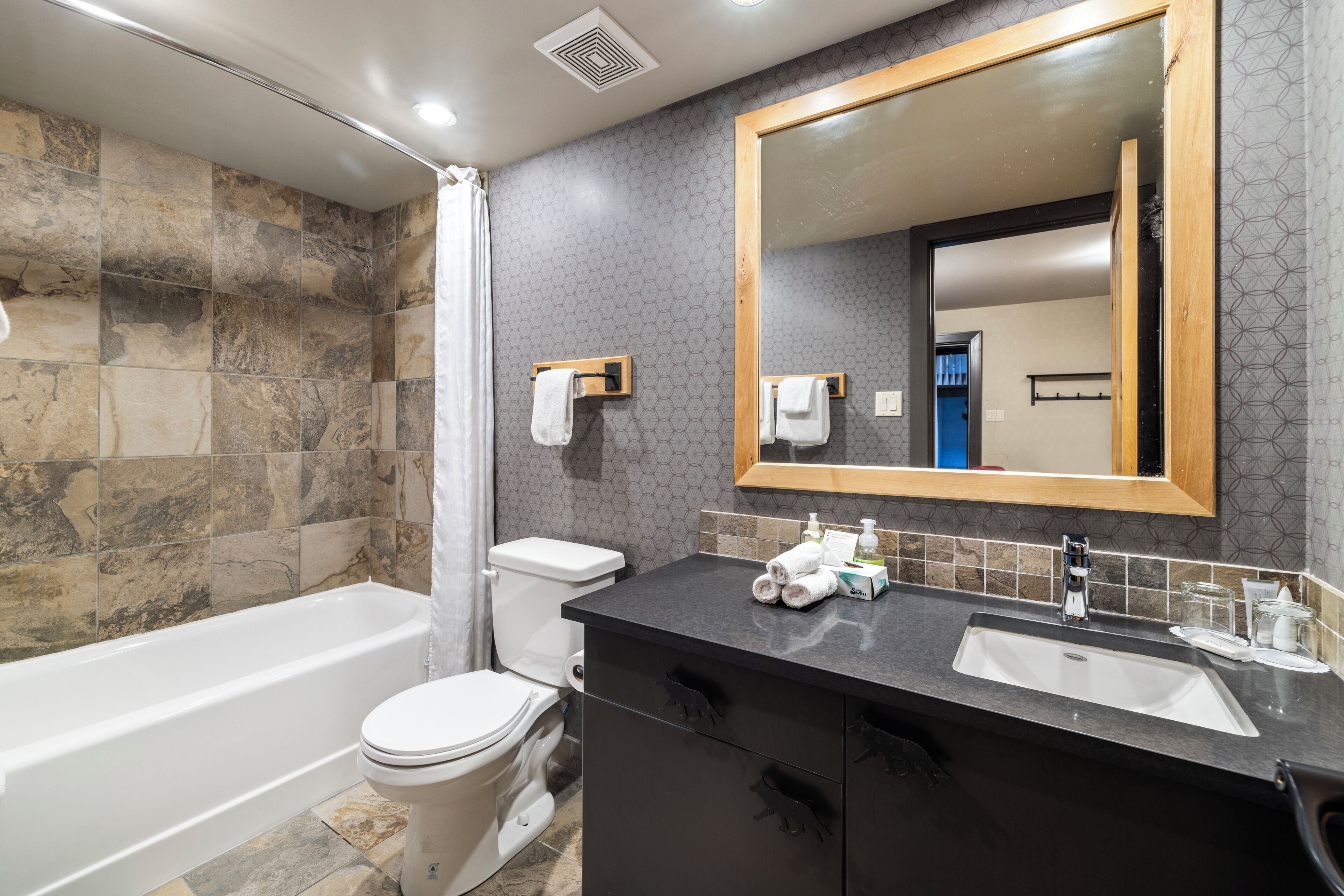 Un baño con bañera, inodoro, tocador con espejo y cortina de ducha.
