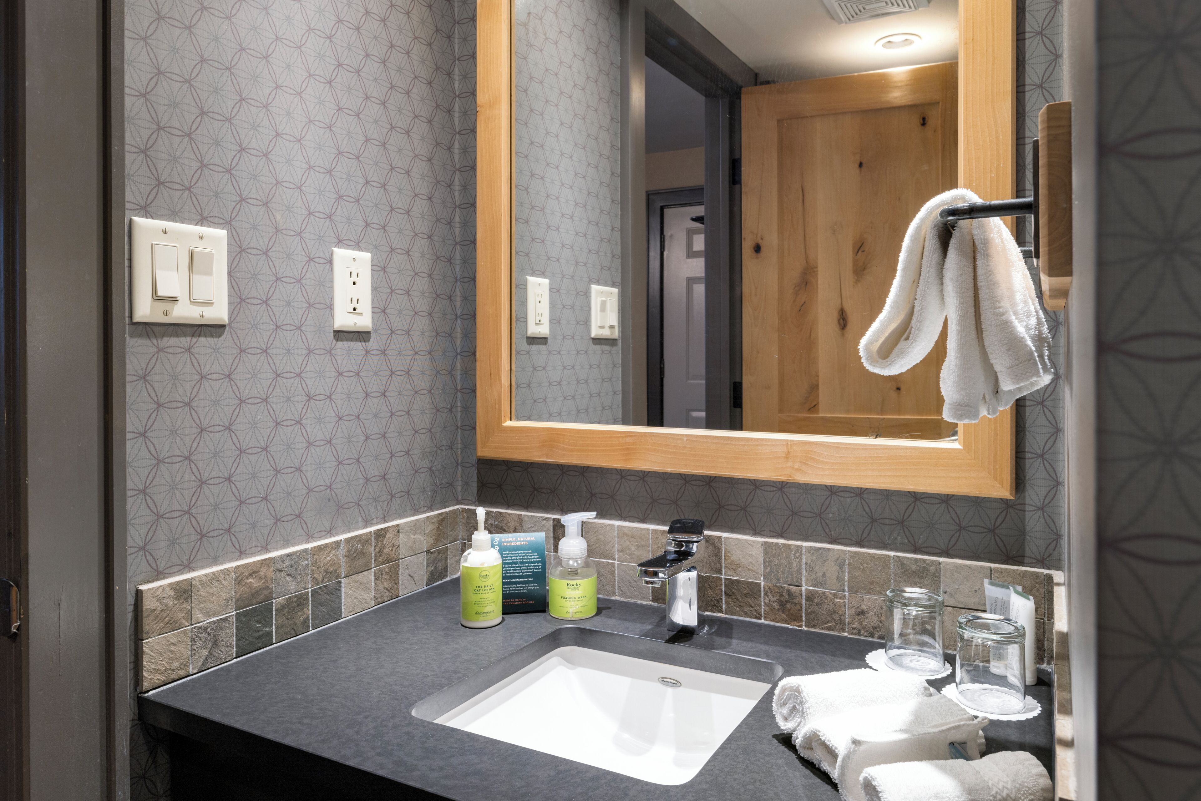 A bathroom with a large mirror, a sink, and toiletries.