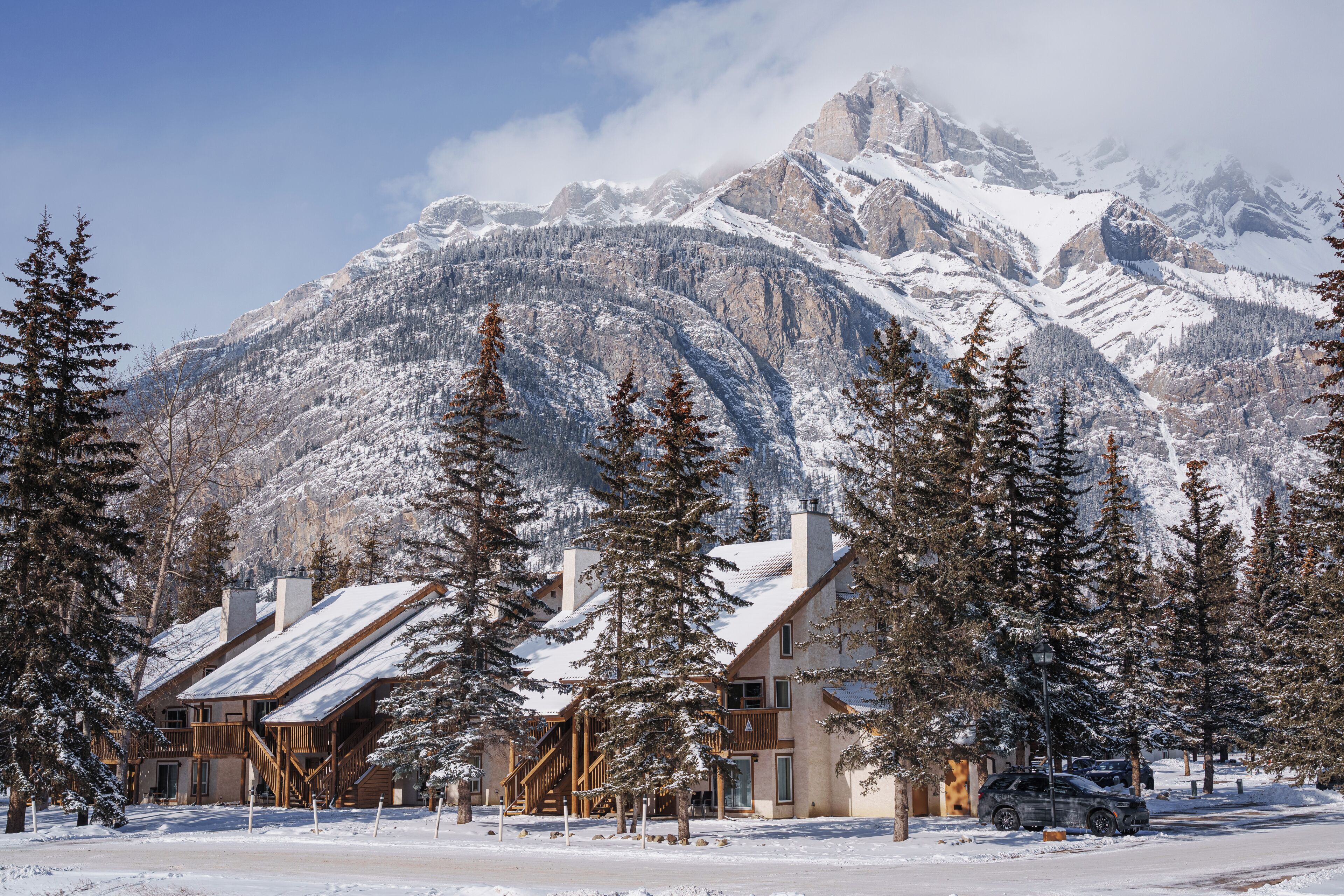 A lodge with a mountain backdrop, featuring a wooden exterior and a snow-covered landscape.