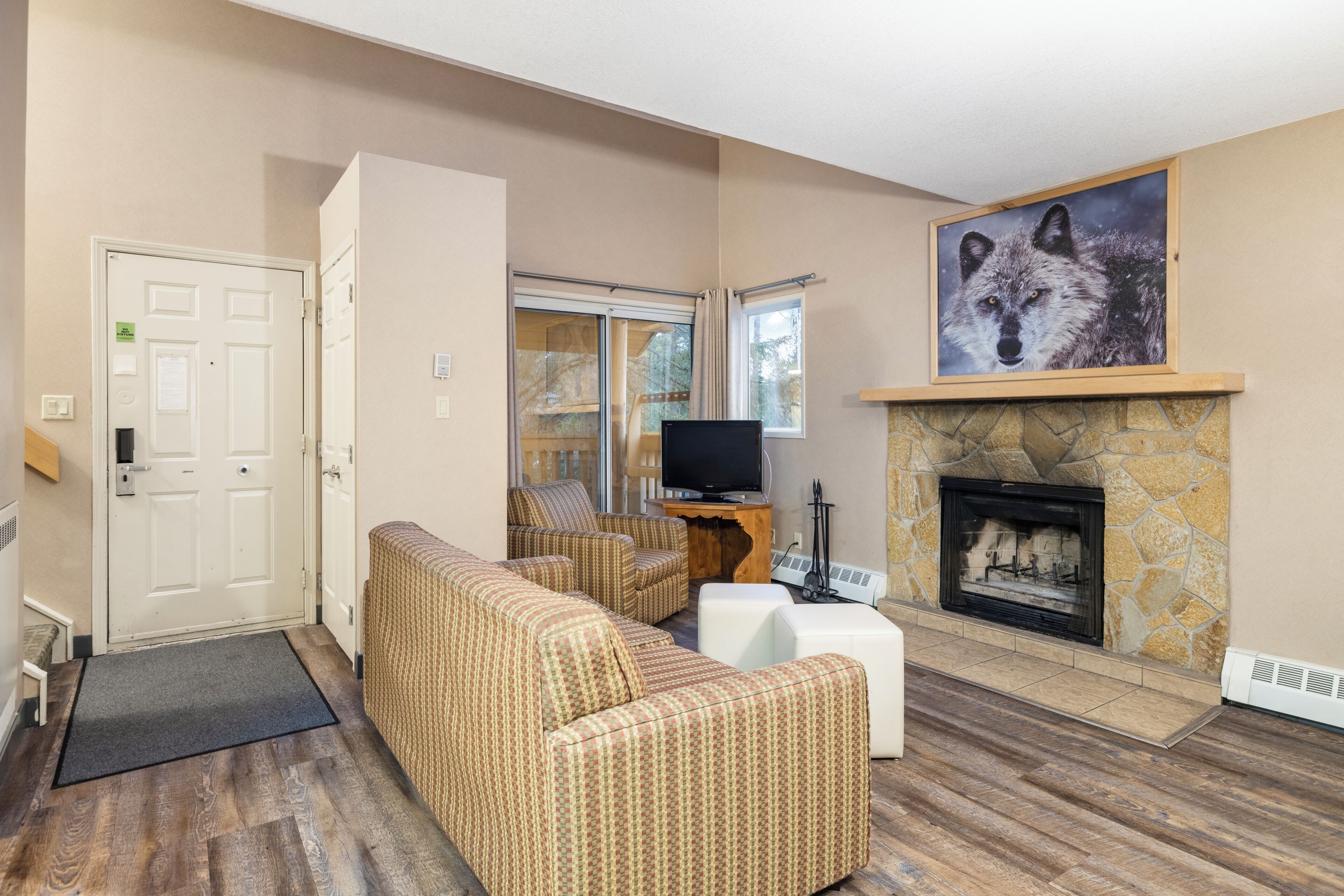 A living room with a stone fireplace, a sofa, a television, and a door.