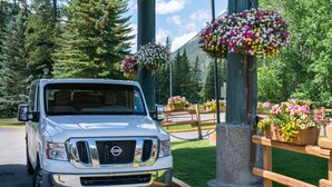Un camion blanc est garé dans un endroit pittoresque, agrémenté de clôtures en bois et de jardinières fleuries.