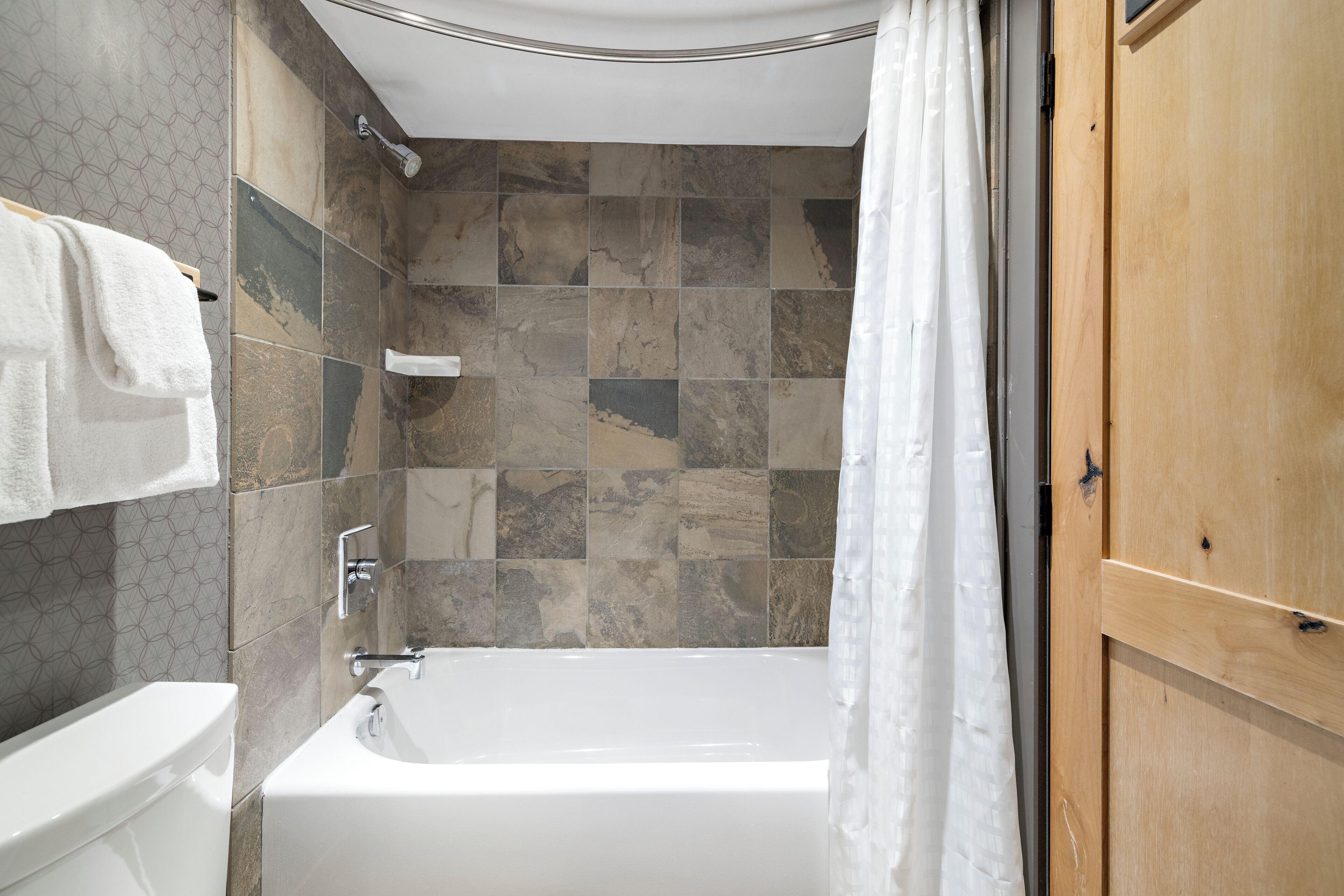 Ein Badezimmer mit Badewanne, Dusche und einer Holztür.