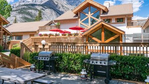 Un chalet doté d’une terrasse en bois, de barbecues et de mobilier d’extérieur.