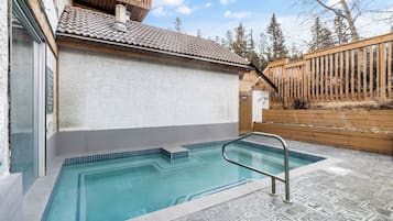Una piscina con muelle de madera y pared blanca.
