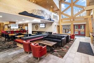 A hotel lobby with a bar area, seating, and a large window.