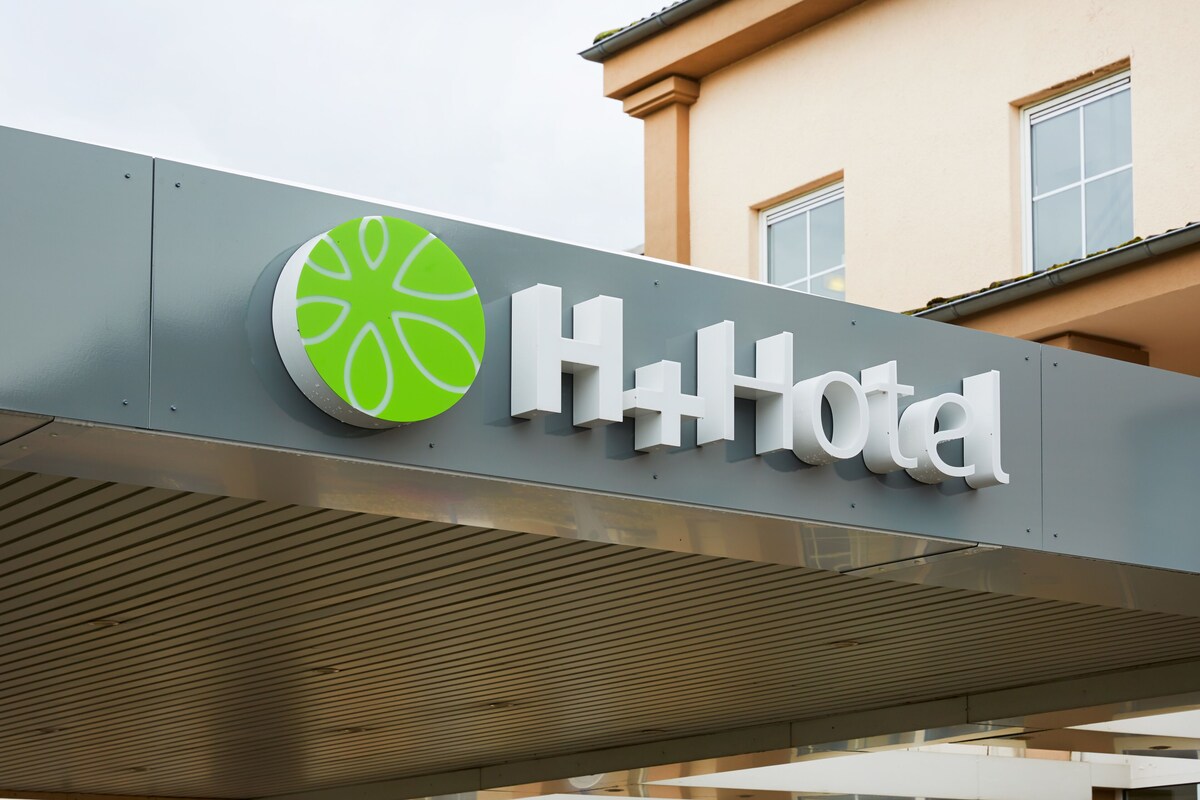 A hotel sign with a green and white logo and the word "Hotel" in white letters.