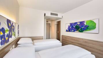 Ein Hotelzimmer mit zwei Betten, einem hölzernen Kopfteil und einem großen Blumenbild an der Wand.