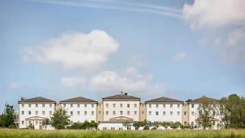 A row of multi-story buildings with a flat roof, likely a hotel or residential complex, with a clear sky above.