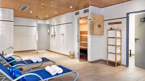 Moderni spa-huone, jossa on puinen katto, valkoisilla laatoilla päällystetyt seinät ja siniset lepotuolit.
