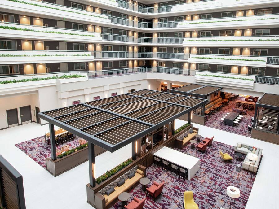 Ett hotell med en atriumgård i flera våningar, ett stort, öppet område i mitten, flera sittgrupper och balkonger med grönska.