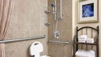 Un baño con ducha, barras de apoyo, inodoro y un perchero para toallas.