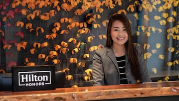 Una mujer está detrás de la recepción, con un cartel que dice "Hilton Honors".