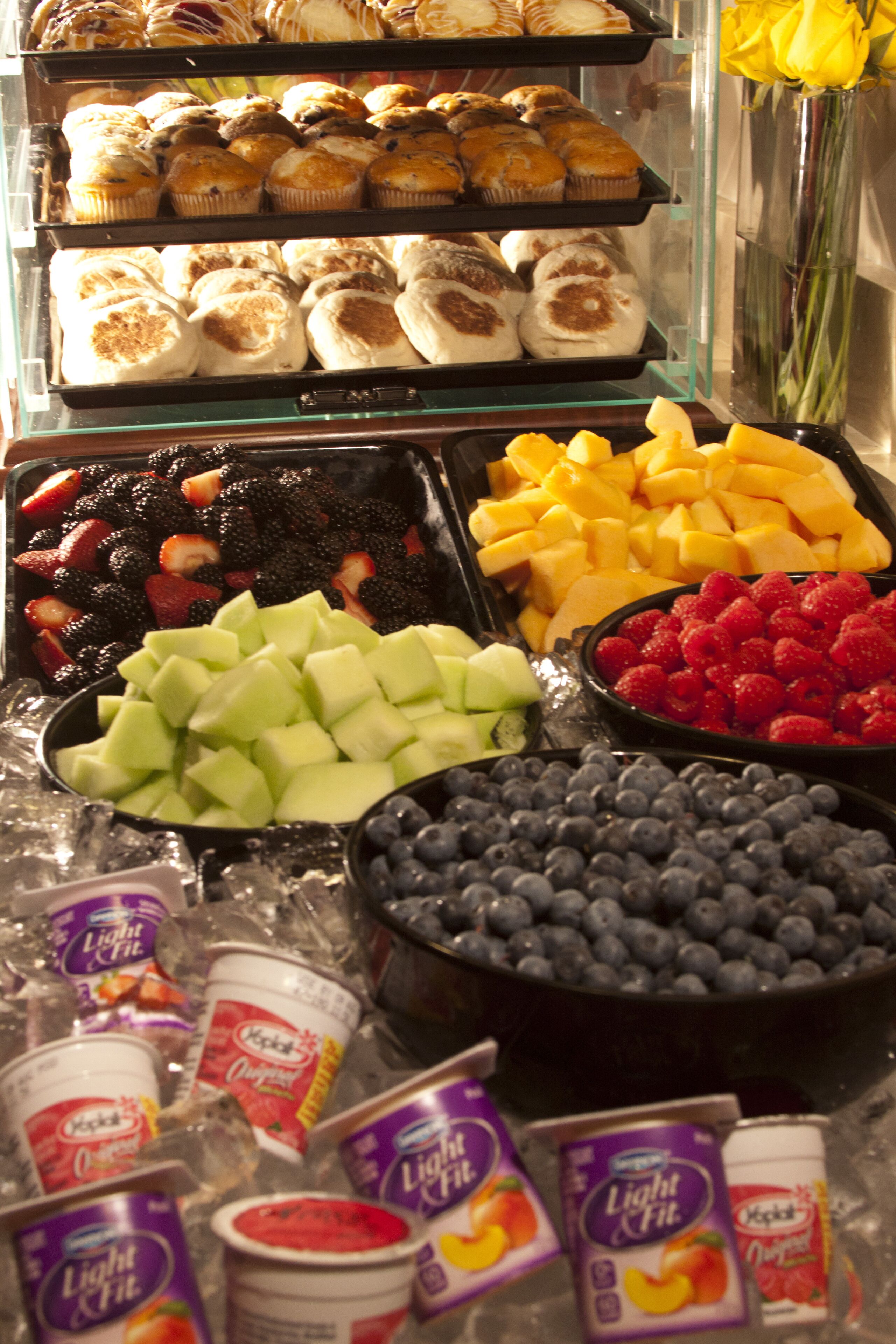 Una exhibición de productos de panadería, frutas frescas y recipientes de yogur.