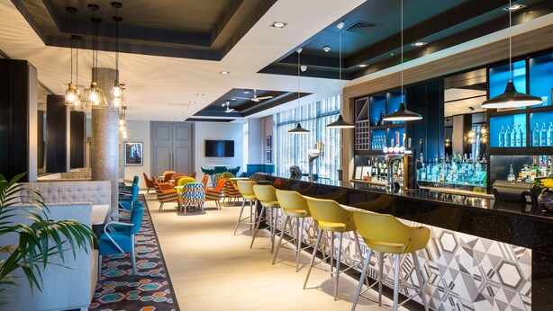 A bar area with a long counter, multiple bar stools, and a seating area with a sofa and chairs.