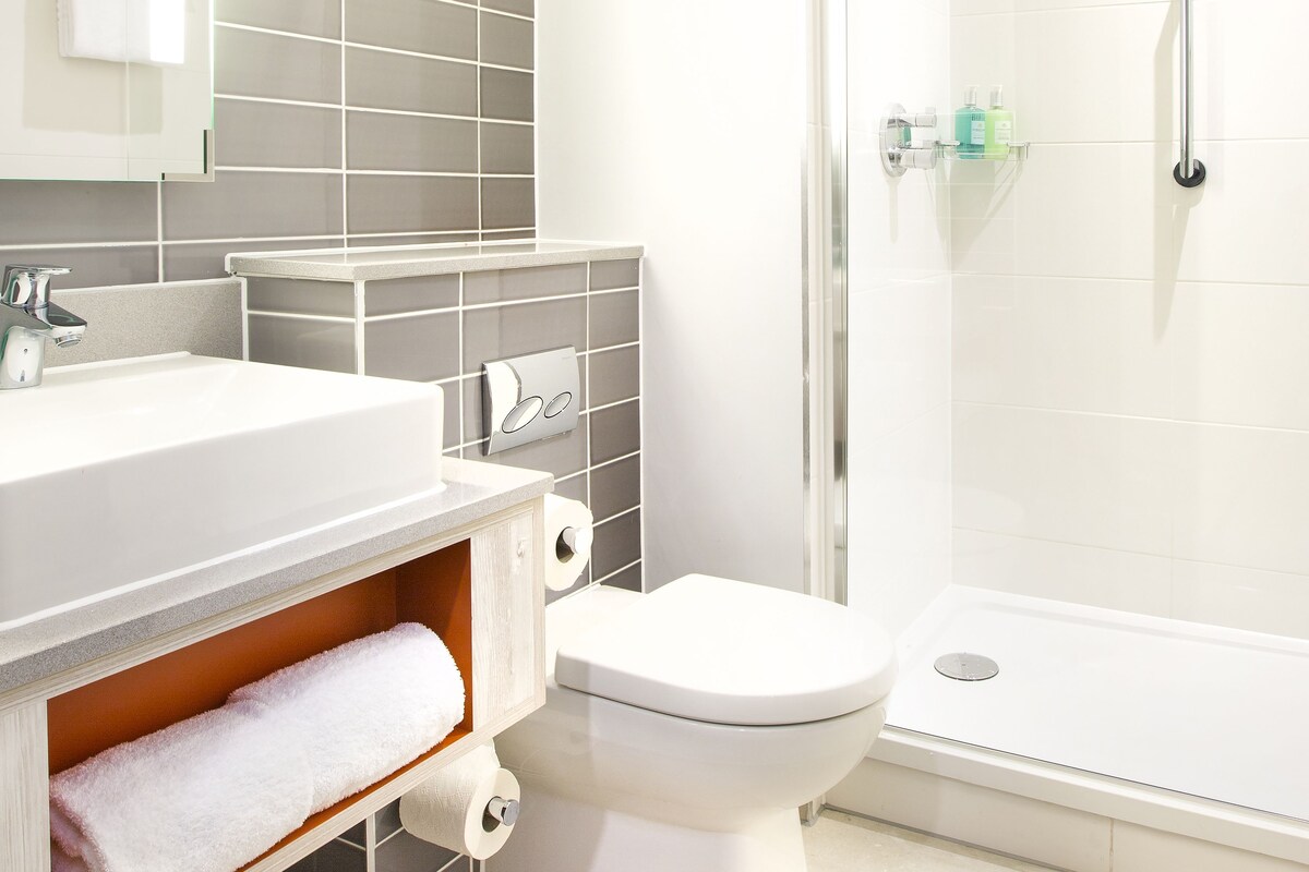 A modern bathroom with a white sink, toilet, and shower.