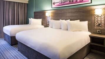 A hotel room with two beds, a cityscape picture on the wall, and a nightstand with a lamp.
