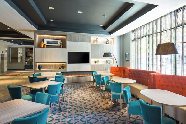 Un espace de détente moderne, doté de sièges, de tables et d’une cheminée.