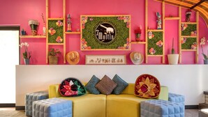 A vibrant living room with a yellow sofa, blue ottomans, and a variety of decorative items including plants and a framed logo. - Best Western Battlefield Inn-Manassas (Manassas)
