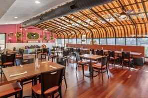 A restaurant with wooden tables and chairs, a curved ceiling, and large windows. - Best Western Battlefield Inn-Manassas (Manassas)