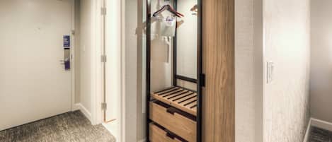 A hallway with a wooden bench, a mirror, and a hanging coat rack.