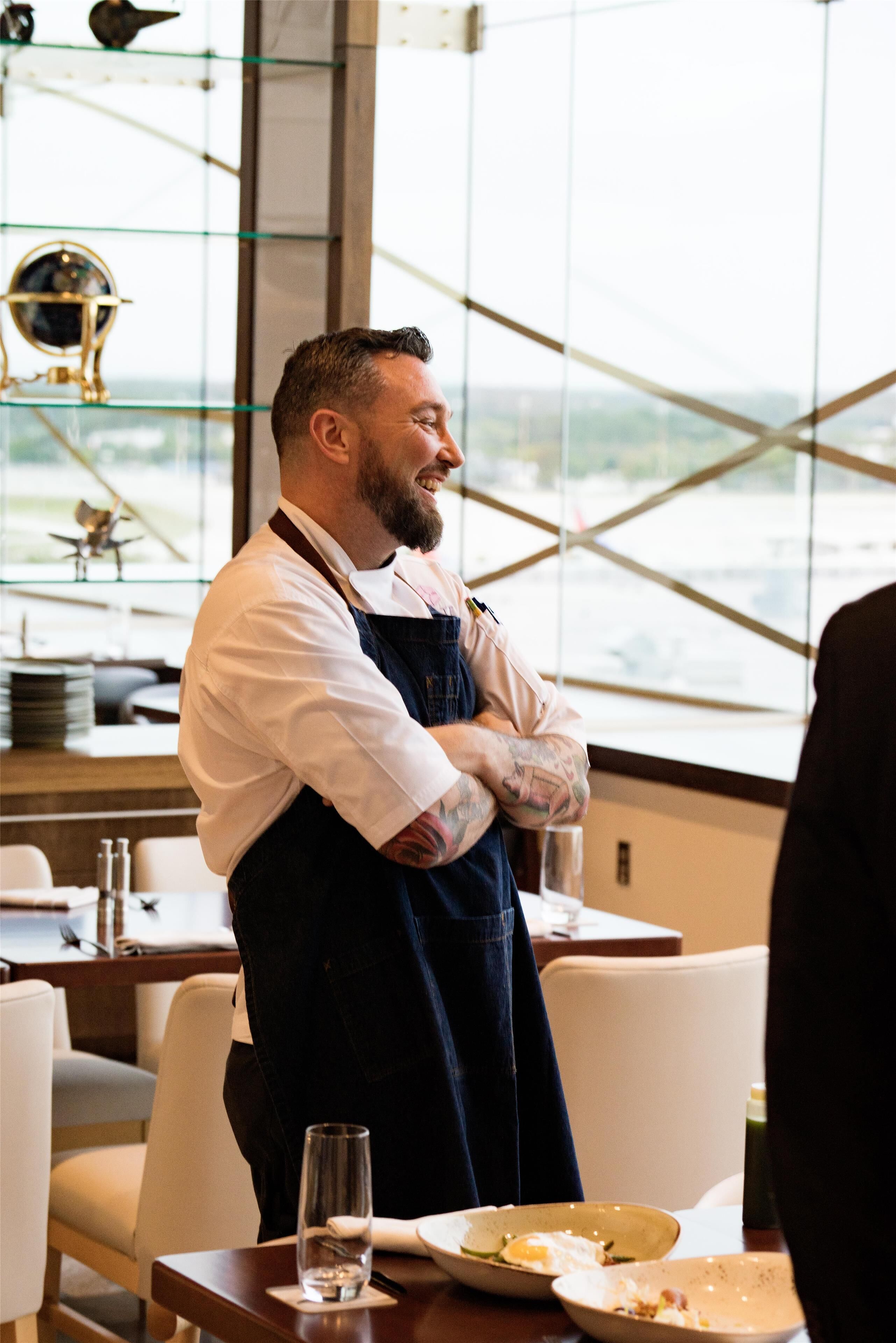 A person standing in a restaurant with a view through large windows.