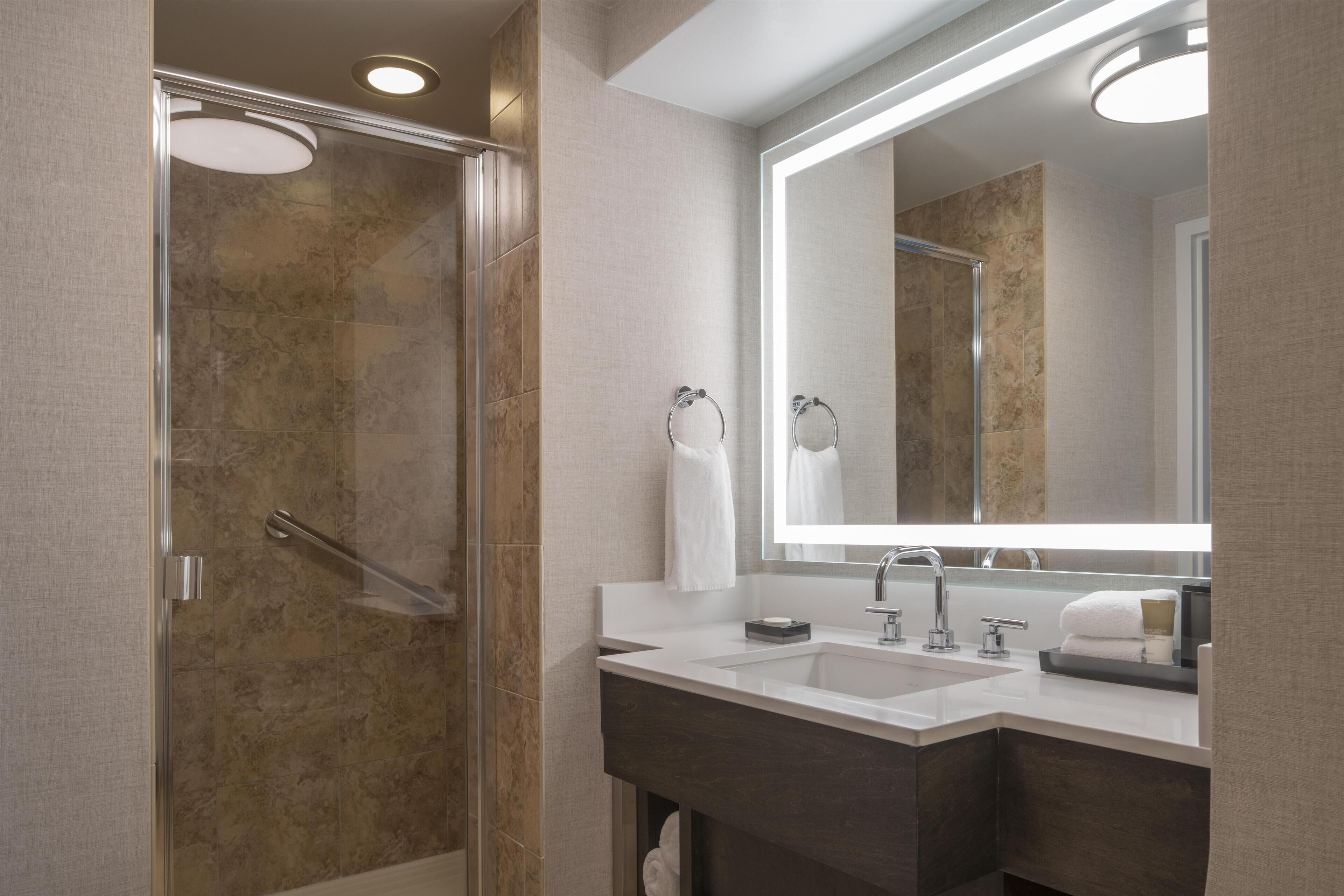 Un baño moderno con cabina de ducha de vidrio, un espejo grande y un mueble de tocador doble.