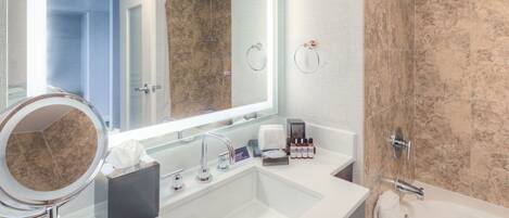 A modern bathroom with a large mirror, a sink, a bathtub, and a shower area.