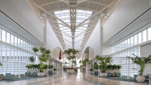 A spacious lobby with high ceilings, large windows, and potted plants. - Hyatt Regency Orlando International Airport (Orlando)
