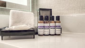 A bathroom with a white towel, a tissue box, and three bottles of body care products.