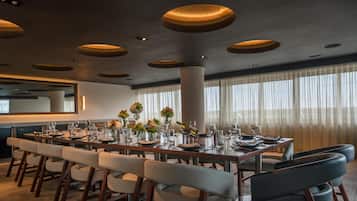 A modern dining area with a long table set for a meal, surrounded by chairs.