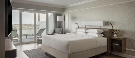 Una habitación de hotel moderna con una cama grande, un escritorio, una silla y vistas a través de puertas de cristal.