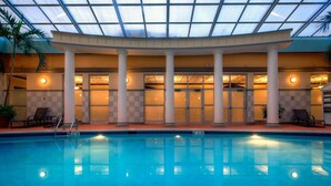 An indoor swimming pool with a glass ceiling, columns, and lounge chairs. - Radisson Hotel Cincinnati Riverfront (Covington)