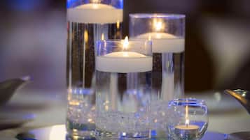 Three glass candle holders with candles, one with ice cubes and one with a smaller candle.