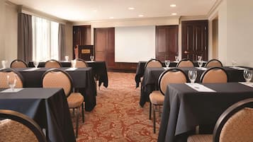 Une salle de conférence équipée de plusieurs tables, de chaises et d’un grand écran.