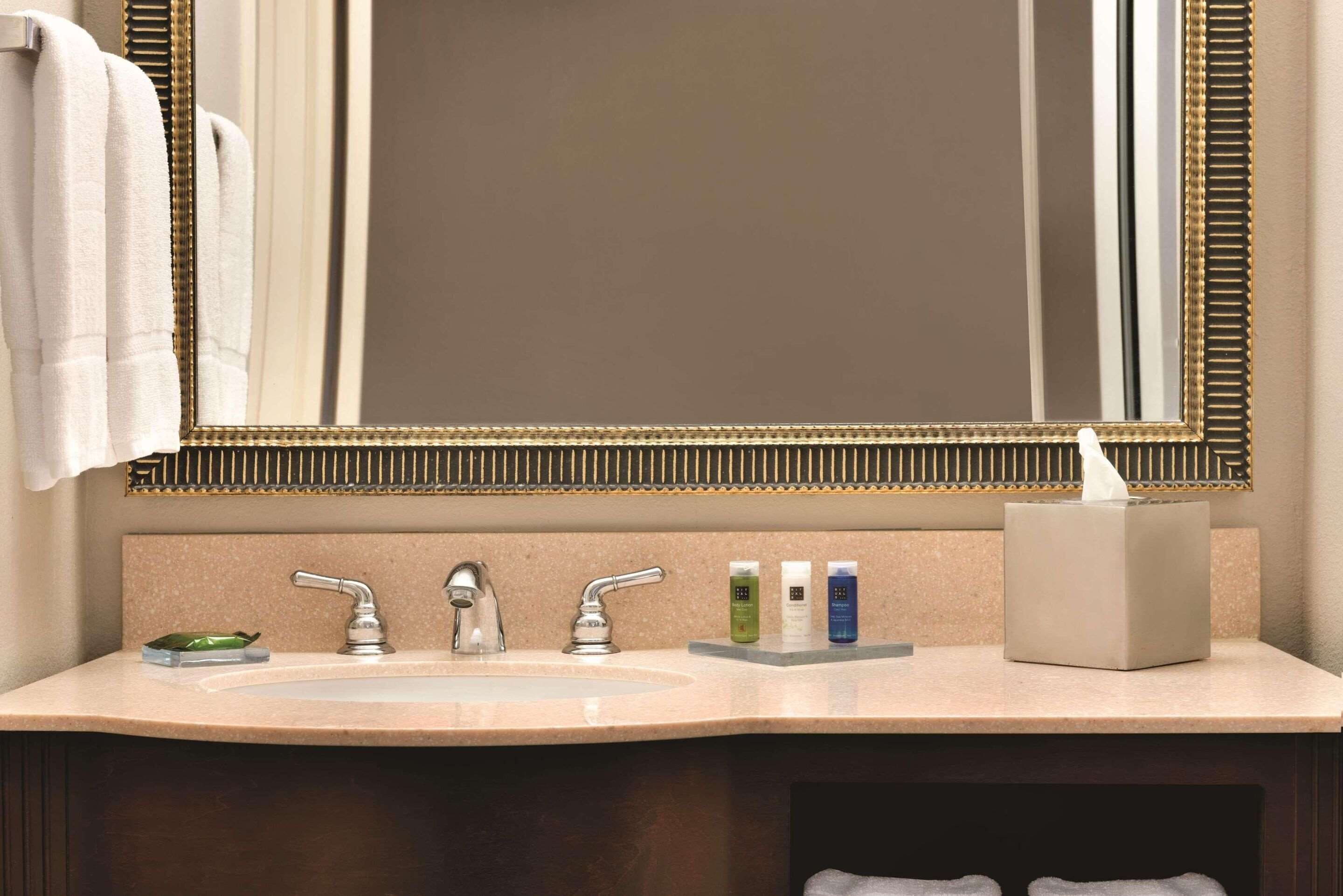 Une salle de bain dotée d’un grand miroir, de deux lavabos et d’articles de toilette.