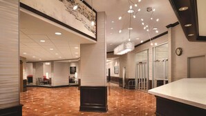 A spacious lobby with a polished marble floor, a reception desk, and a modern chandelier. - Radisson Hotel Cincinnati Riverfront (Covington)