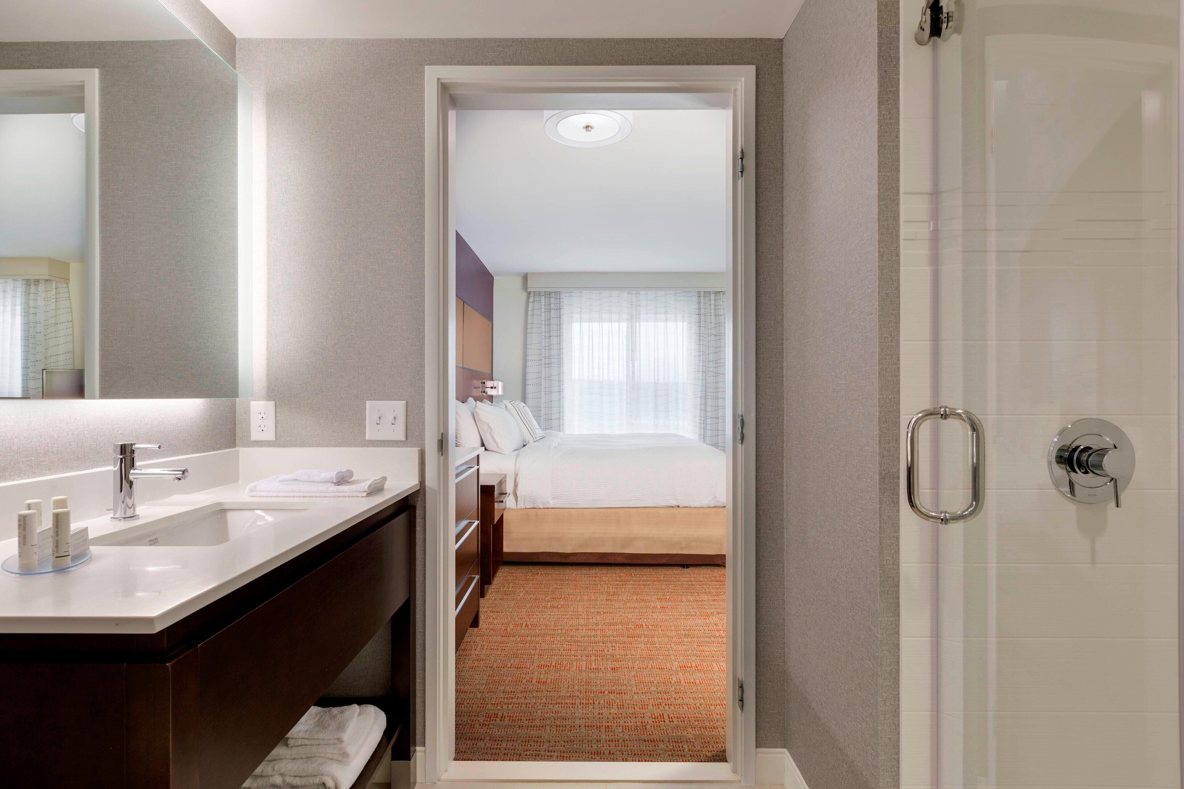 A hotel room with a bathroom, a bed, and a shower.