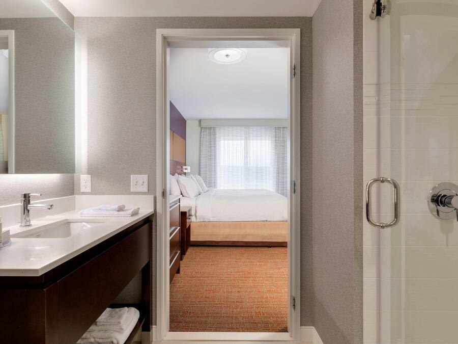 A hotel room with a bathroom, a bed, and a shower.