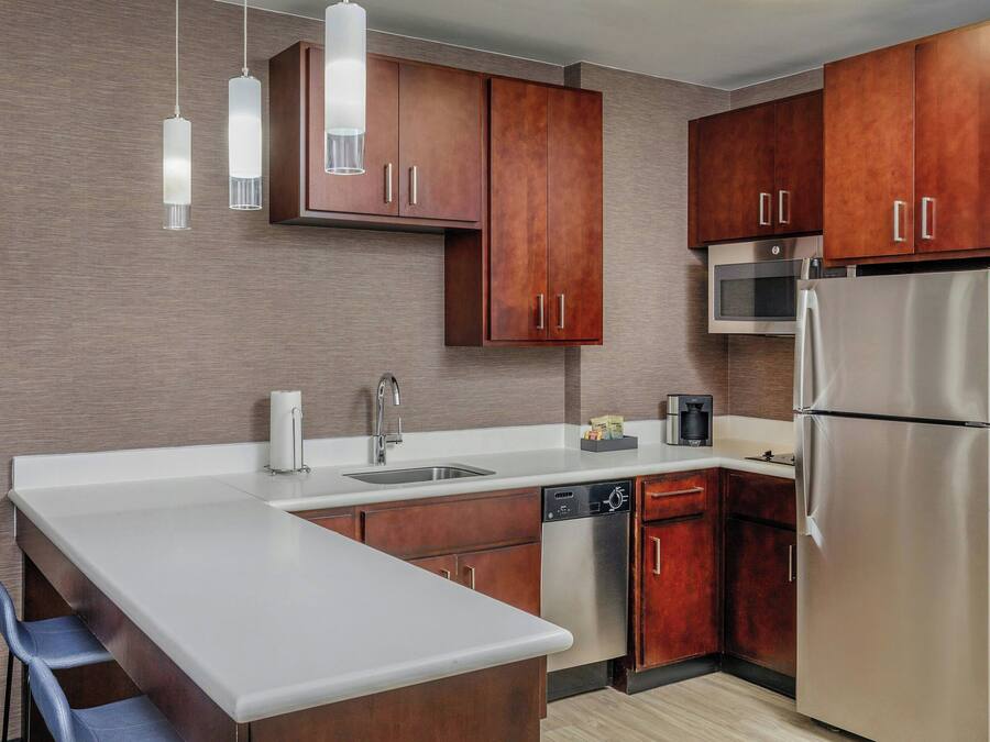 Una cocina moderna con armarios de madera, electrodomésticos de acero inoxidable e iluminación colgante.