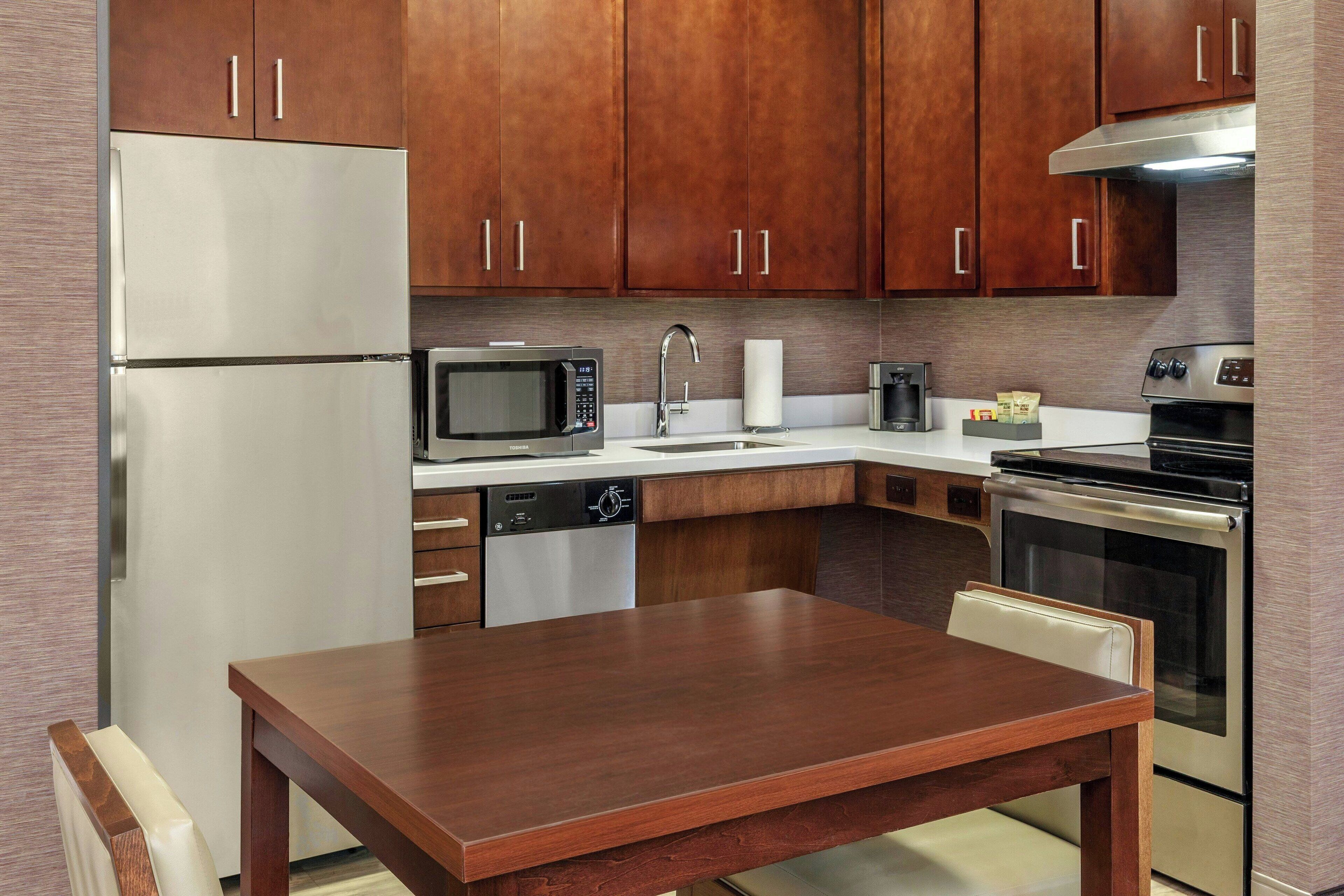 A modern kitchen with wooden cabinets, stainless steel appliances, and a wooden dining table.