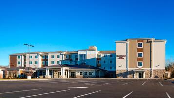 A multi-story hotel with a parking lot in front.