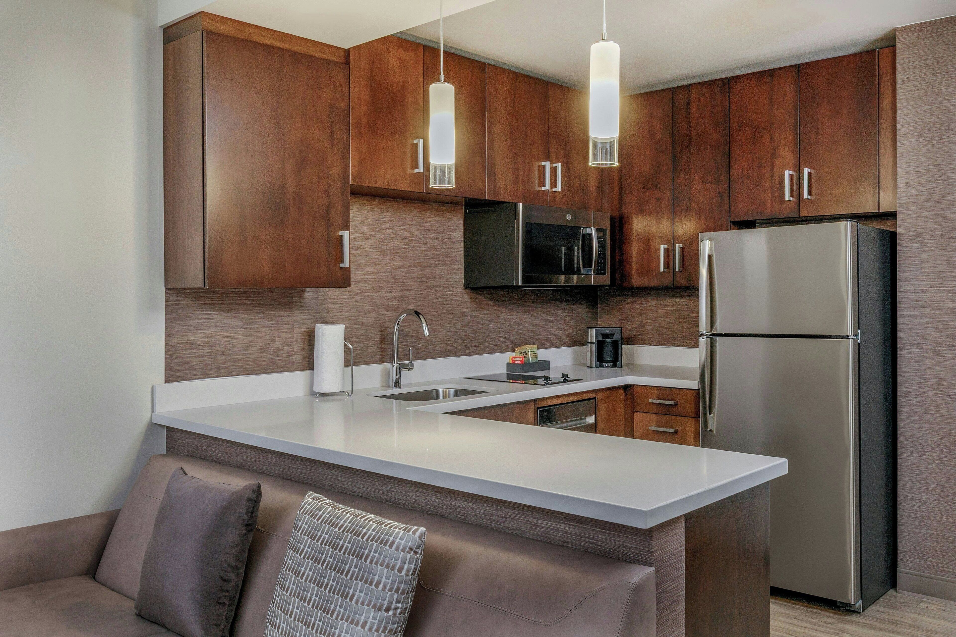 Una cocina moderna con armarios de madera, electrodomésticos de acero inoxidable y una encimera blanca.