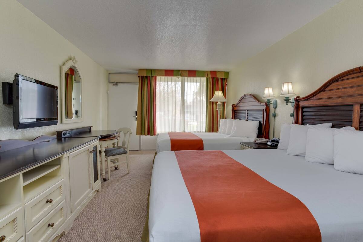 Une chambre d’hôtel avec deux lits, une télévision, un bureau et une chaise.
